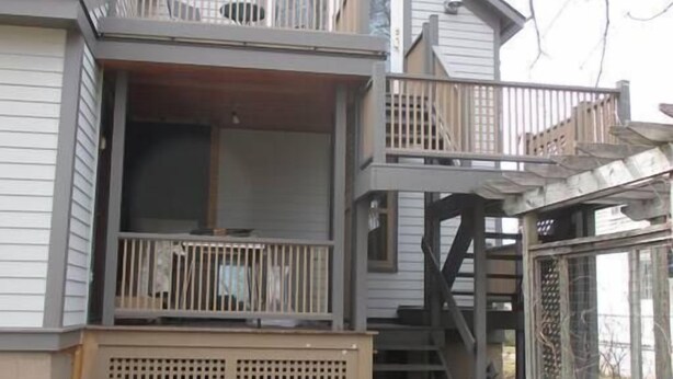 A two-story house with a balcony, a staircase, and a covered porch area.