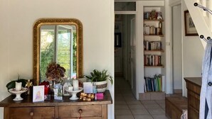 Una scala con ringhiera bianca conduce a un secondo piano. Sotto, si vede un tavolino consolle in legno con uno specchio e oggetti decorativi.