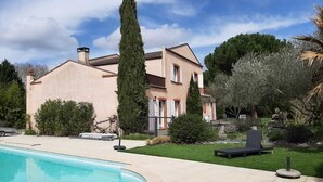 Un'ampia casa con piscina, immersa in un giardino curato e omaggiata da un albero secolare.