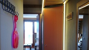 Ein Flur mit einer Holztür, einem roten Gegenstand an der Wand und einer Bank im Hintergrund.
