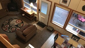 A cozy living room with a fireplace, a sofa, a coffee table, and a dining area with chairs and a table.