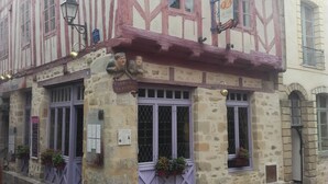 Un edificio tradicional de entramado de madera con muros de piedra y vigas de madera, con varias ventanas y un letrero de restaurante.