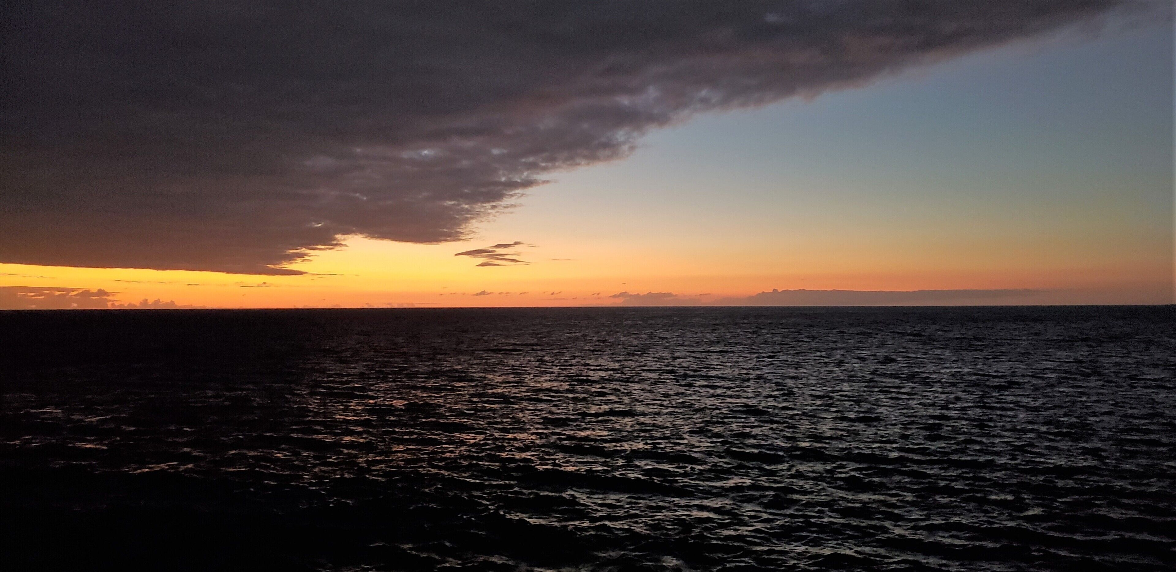 Tramonto su uno specchio d'acqua con formazione nuvolosa scura.