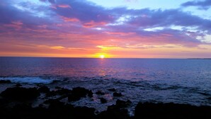 A sunset over the ocean with a rocky shoreline. - Amazing Direct Ocean Front Condo - Beautiful Sunsets, watch dolphins and whales (Kailua-Kona)
