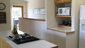 A kitchen with a white countertop, a microwave on a wooden shelf, and a refrigerator. - Views for Days Mountain Retreat.  License#6025  (Estes Park)