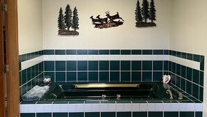 A bathroom with a freestanding bathtub, a skylight, and wall-mounted deer and tree decorations. - Views for Days Mountain Retreat.  License#6025  (Estes Park)