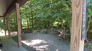 Un espacio al aire libre techado con un sendero de grava, un muelle de madera y un hogar de piedra.