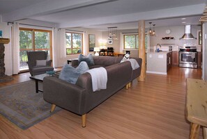 A living room with a sofa, a dining table, and a kitchen area with a stove. - Aspen at Outrun, Great renovated 3 BR, Hot tub (Crested Butte)