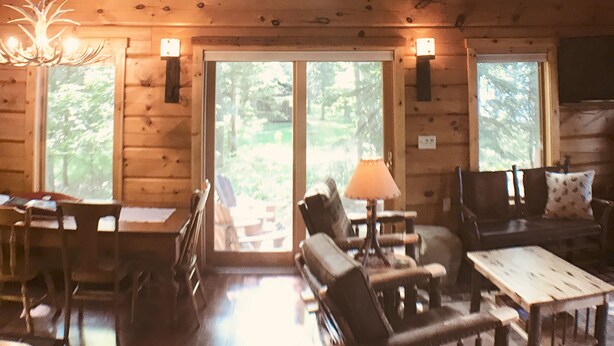 A log cabin interior with a high ceiling, multiple windows, wooden furniture, and a chandelier. - SUMMER fun in a cozy log lake home on the Whitefish Chain under the tall pines (Crosslake)