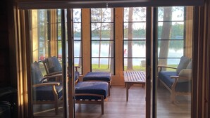 A cabin with a sliding glass door leading to a deck with outdoor seating and a view of a lake. - SUMMER fun in a cozy log lake home on the Whitefish Chain under the tall pines (Crosslake)