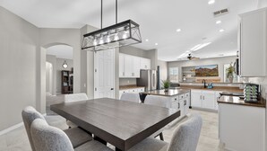 A modern kitchen with white cabinets, stainless steel appliances, and a dining area with a large table and chairs.
