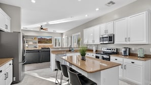 A modern kitchen with white cabinets, a granite countertop, a stainless steel refrigerator, and a built-in oven.