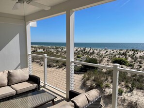 A balcony with a view of the beach and ocean.