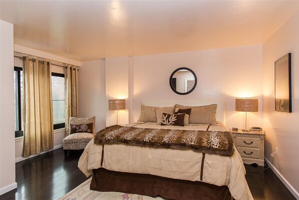 Cozy retreat with a large bed, bedside tables, and a round mirror.