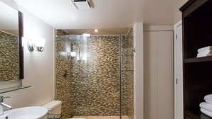 Une salle de bain moderne avec une douche à parois de verre, un lavabo blanc et des toilettes.