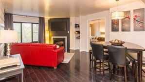 Un salon moderne avec un canapé rouge, un coin repas comprenant une table et des chaises, et une cheminée.