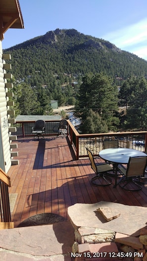 Enjoy a serene mountain view from this outdoor deck with a table and chairs.