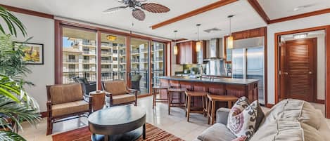 A spacious living area with a sofa, chairs, a coffee table, and a kitchen area with a bar.