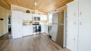 A kitchen with white cabinets, stainless steel appliances, and a wooden ceiling.
