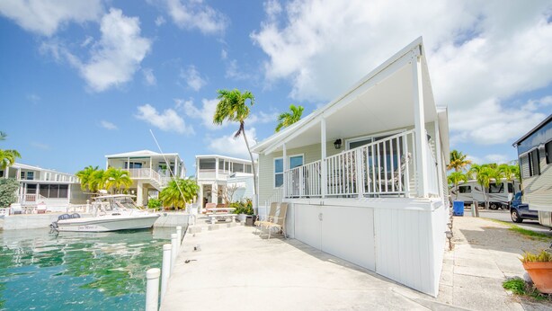 A waterfront property with a covered porch, a boat dock, and a clear sky.