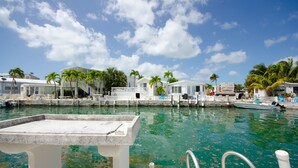 A marina with boats, a dock, and a white building with a balcony.