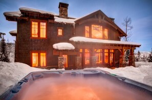 A large log cabin with multiple windows and a hot tub in the foreground. - Available 12/19-12/26. Luxury Home Huge Bedrooms Perfect for Multiple Families. (Park City)