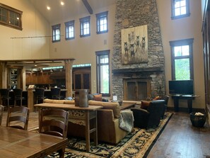 A spacious living area with a stone fireplace, a large painting above it, and a television on a stand. - Available 12/19-12/26. Luxury Home Huge Bedrooms Perfect for Multiple Families. (Park City)