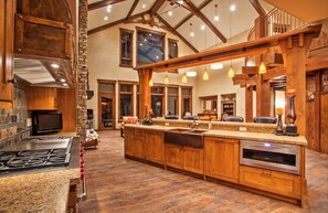 A spacious kitchen with a large island, wooden beams, and a stone accent wall. - Available 12/19-12/26. Luxury Home Huge Bedrooms Perfect for Multiple Families. (Park City)