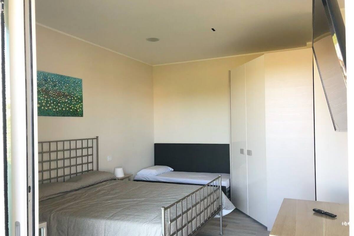 A bedroom with two beds, a desk, and a painting on the wall.
