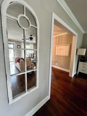 A room with a large arched window, wooden flooring, a bed, a desk, and a framed artwork on the wall. - Charming Midtown Home near Fairgrounds/TU/Downtown (Tulsa)