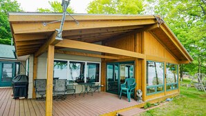 A wooden deck with outdoor furniture, a covered patio, and a dog statue. - Bigbay vacation home on Lake Independence. (Bigbay)