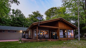 A wooden cabin with a porch, large windows, and a satellite dish. - Bigbay vacation home on Lake Independence. (Bigbay)