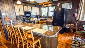 A kitchen with wooden cabinets, a granite countertop, and a central island with bar stools. - Bigbay vacation home on Lake Independence. (Bigbay)