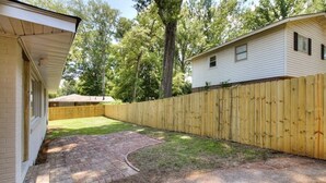 A residential property with a brick patio, wooden fence, and a grassy yard. - The Masters Rental! Less than half a mile from course! (Augusta)