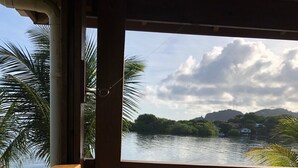 Une terrasse en bois offrant une vue sur un lac paisible, entourée de verdure et de collines.