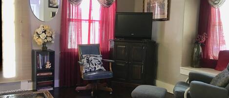 A living room with a television on a cabinet, two armchairs, a coffee table, and a rug.