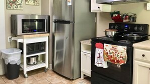 Une cuisine compacte équipée d’un réfrigérateur en acier inoxydable, d’un four à micro-ondes, d’une cuisinière et d’un petit placard.