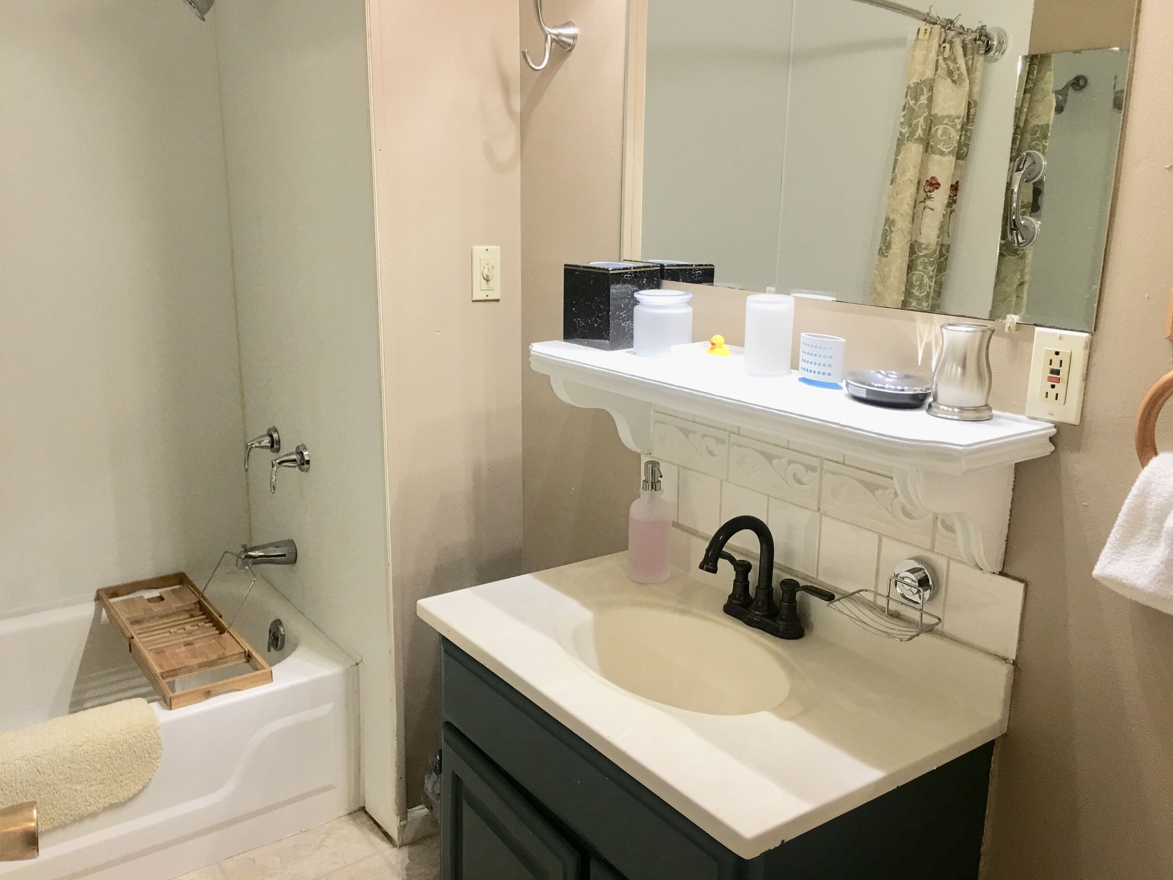 A bathroom with a bathtub, a sink with a mirror above it, and a shower area.