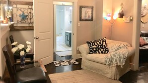 Un salon comprenant un canapé, un fauteuil, une table basse et un vase décoratif avec des fleurs.