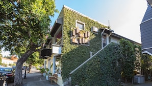 A two-story house with a green ivy-covered exterior, a visible staircase, and a front porch with outdoor seating.