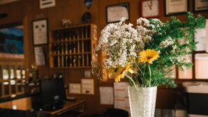 Un mostrador de recepción con un florero, paneles de madera, un reloj y diplomas enmarcados en la pared.
