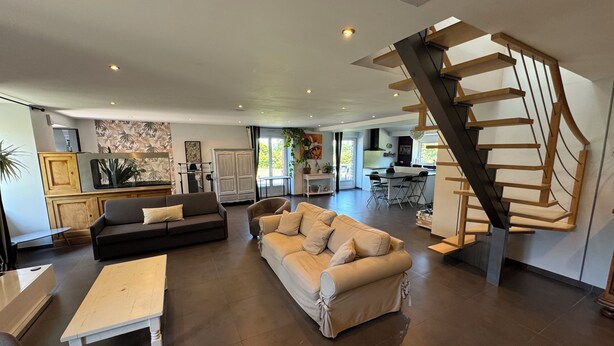 A spacious living area with a modern staircase, a dining area, and a kitchen with wooden cabinets. - La Maison de Benjamin (La Chapelle-Saint-Aubert)