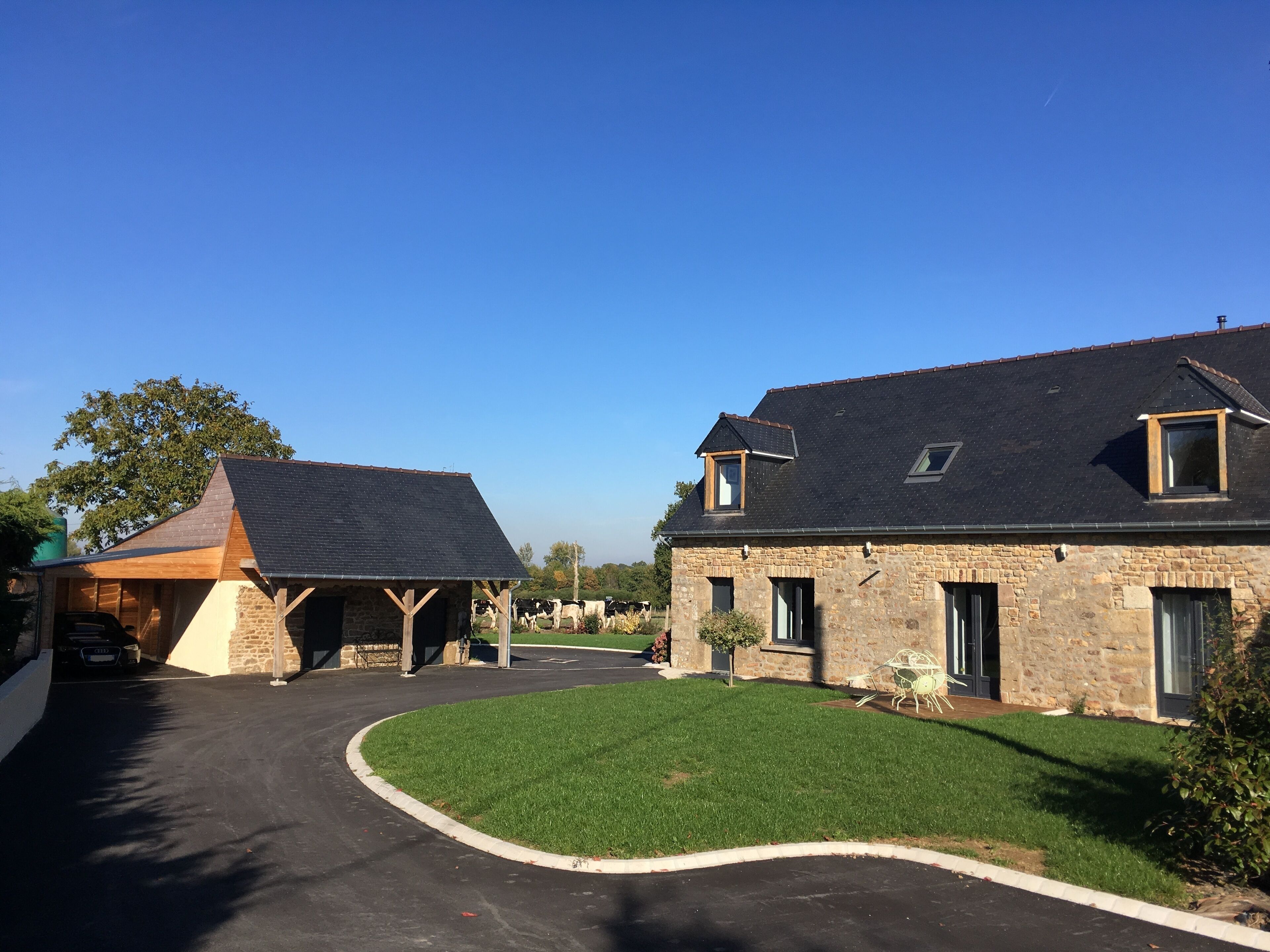A two-story stone house with a covered carport and a well-maintained lawn.