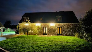 A stone house with a well-lit entrance and a grassy lawn. - La Maison de Benjamin (La Chapelle-Saint-Aubert)