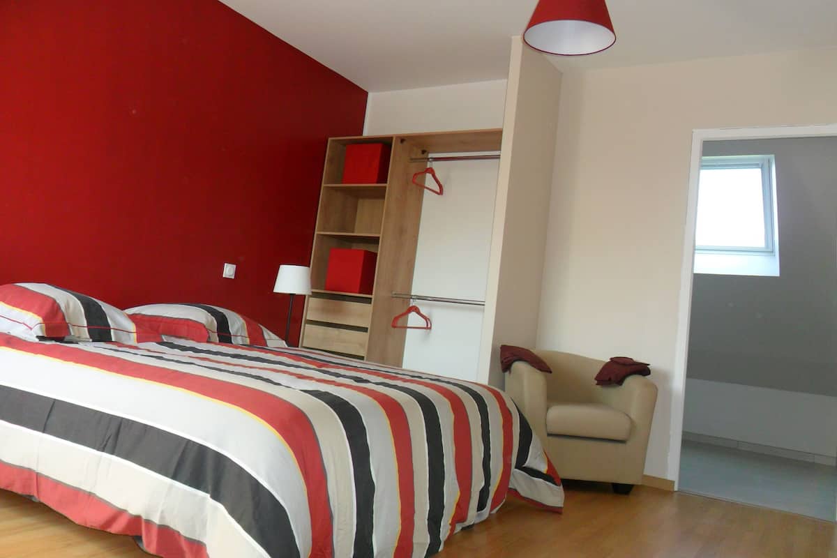 Ein Schlafzimmer mit einem Bett, einem Kleiderschrank, einem Stuhl und einem Fenster.