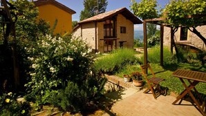 A rustic stone house with a tiled roof, surrounded by lush greenery and flowering plants. - Olimpia - Spacious stone villa with private terrace overlooking the pool (Bologna)