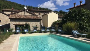 A clear swimming pool with lounge chairs and a stone building in the background. - Olimpia - Spacious stone villa with private terrace overlooking the pool (Bologna)