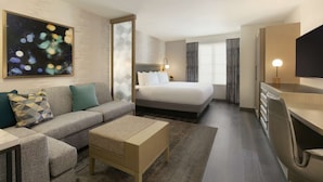 Quarto de hotel moderno com sofá, cama, escrivaninha e televisão.
