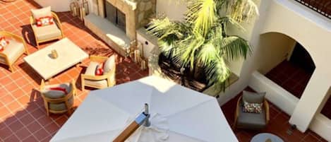 Eine Terrassenanlage im Freien mit einem großen Sonnenschirm, Sitzgelegenheiten und einem Kamin aus Stein.