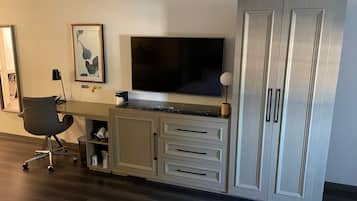 A modern office space with a desk, chair, television, and storage cabinets.
